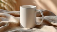 White ceramic coffee mug on soft beige fabric with gentle shadows and warm sunlight, minimalist composition for lifestyle and beverage photography.