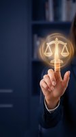 Hand of a professional in business attire pointing at a glowing scales of justice symbol, representing law, legal services, compliance, and ethical business practices in corporate environments.