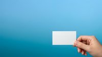 Hand holding blank white business card against gradient blue background for branding and corporate identity mockup purposes.