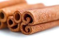 Aromatic cinnamon sticks in macro view showing detailed texture and natural spice pattern, selective focus on rolled bark creates depth and culinary appeal.