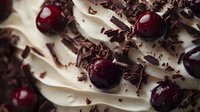 Fresh cherries nestled in swirls of white cream frosting, topped with dark chocolate shavings creating an elegant dessert composition. Perfect for culinary designs.