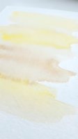 Abstract watercolor brush strokes in soft yellow and beige tones on white paper creating organic flowing shapes for artistic backgrounds and creative projects.