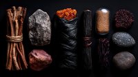 Aromatic spices and minerals arranged in dark moody composition on black background, including cinnamon sticks, raw stones, dried chili peppers and exotic seasonings.