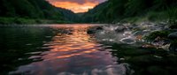 Serene mountain lake at sunset with golden light reflecting on calm water, surrounded by dense forest and rocky shores during twilight hour.