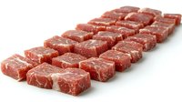 Raw beef cubes arranged in neat rows on white background, fresh premium meat cuts showing marbling texture and rich red color, isolated for culinary use.
