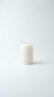 White pillar candle with a burning flame on a clean light background, evoking calm, spirituality, and warmth for home decor and wellness concepts.
