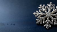 Glittering silver snowflake decoration with intricate crystalline pattern on dark blue background creates festive winter holiday atmosphere. Macro photography reveals detailed texture.