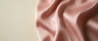 Luxurious pink silk fabric with elegant flowing waves and soft drapes creating smooth textures and gentle shadows on neutral background for fashion design.