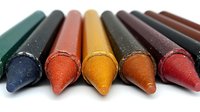 Colorful wax crayons lined up in row showing tips on white background, macro close-up view. Art supplies for drawing and coloring, isolated with selective focus.