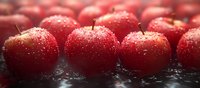 Fresh red apples with water drops on dark surface in panoramic view. Ripe fruits with natural moisture and vibrant color create appetizing composition.