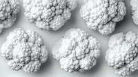 Fresh cauliflower florets arranged in rows on light gray background, top view. Minimalist food composition with organic vegetables isolated.