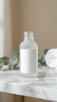 Frosted glass cosmetic bottle with blank white label on marble surface with eucalyptus leaves and towel in soft natural lighting for skincare branding.