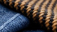 Textured fabric close-up showing woven brown and black pattern against blue denim material, highlighting contrast in textile design for fashion and upholstery applications.