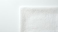 White foam padding material corner detail showing soft cushioning texture for furniture upholstery and protective packaging applications.
