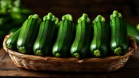 Fresh green zucchini squash arranged in wicker basket on rustic wooden table, natural lighting highlights glossy skin texture and farm-fresh produce quality.