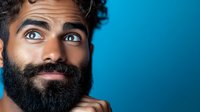 Middle-aged bearded man with curly hair looking up thoughtfully against blue background, expressing curiosity and contemplation for business concepts.