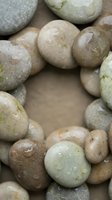 Smooth wet river rocks and pebbles in natural earth tones creating organic texture for spa wellness meditation zen garden landscaping design backgrounds.