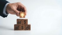 Businessman hand placing wooden block with glowing light bulb icon on top of pyramid, symbolizing innovation, strategy, and business growth.