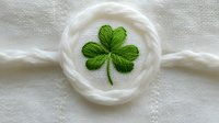 Embroidered green shamrock on white linen fabric with decorative circular rope border, perfect for St. Patrick's Day designs and Irish-themed crafts.