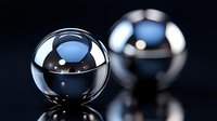 Metallic chrome spheres with reflective surfaces on dark background showing mirror effect and light reflections. Professional product photography style.