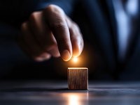 Businessman touching glowing cube with magical light effect on dark background, representing innovation, potential and business transformation concept.