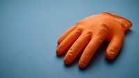 Isolated orange rubber hand mannequin on blue background, suitable for display, retail, fashion design, and commercial product presentations.
