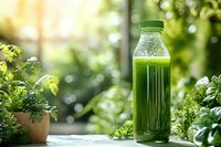 Fresh green juice smoothie bottle on wooden table with herbs and plants in bright natural kitchen setting for healthy lifestyle and detox diet.
