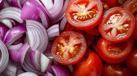 Fresh sliced red onions and ripe tomatoes arranged as colorful cooking ingredients for healthy meal preparation and culinary recipes.