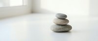 Zen stone stack on white surface in bright minimalist room for meditation wellness spa relaxation mindfulness balance harmony interior design concepts.