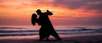 Romantic couple dancing tango silhouette on beach at sunset with dramatic orange and pink sky. Perfect for wedding, romance and dance concepts.