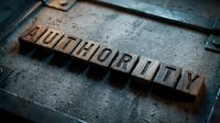 Vintage wooden letterpress blocks spelling AUTHORITY on a dark metal surface, conveying power, leadership, and control in a retro typography concept.