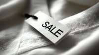 White clothing tag with SALE text in black letters on soft fabric, highlighting retail discount promotion for fashion industry.