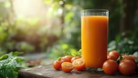 Fresh tomato juice in glass with ripe red tomatoes on wooden table in garden setting with natural sunlight for healthy lifestyle and nutrition.