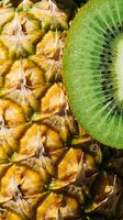 Close-up of fresh pineapple texture with a sliced kiwi, showcasing vibrant tropical fruits for food, nutrition, and healthy lifestyle concepts.