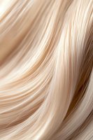 Smooth flowing blonde hair strands in close-up macro shot showing silky texture and natural shine with gentle waves and curves creating abstract pattern.