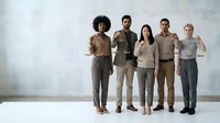 Diverse group of young professionals standing together in neutral clothing against white background for business teamwork concepts.