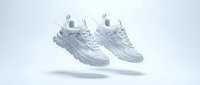 Pair of white chunky sneakers floating in the air against a light gray background, showcasing modern athletic footwear design.