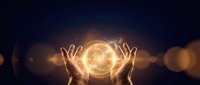 Hands reaching toward glowing golden orb with mystical energy and bokeh lights against dark background for spiritual and metaphysical concepts.
