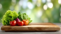 Fresh red tomatoes and green lettuce on wooden cutting board against blurred natural background with bokeh lights, healthy cooking concept.