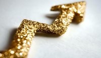 Shimmering golden arrow points upward against white background, featuring glittering texture and bokeh effect, symbolizing growth and success in business concepts.
