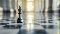 Black king chess piece standing alone on checkered board with dramatic lighting and blurred background creating atmospheric business strategy scene.