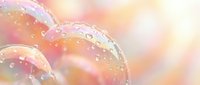 Delicate soap bubbles floating with rainbow reflections and water droplets against soft pastel background for relaxation and wellness concepts.
