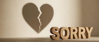 Wooden letters spelling SORRY cast a broken heart shadow on a beige wall, symbolizing apology, regret, and emotional healing in relationships.