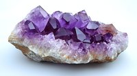 Raw amethyst crystal cluster with deep purple geometric formations growing from white quartz matrix base, displaying natural crystalline structure and color gradients.