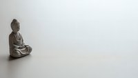 Bronze Buddha statue in meditation pose on clean white background with copy space for mindfulness and spiritual wellness concepts.