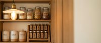Wooden pantry shelves displaying organized storage jars and containers with labeled ingredients, cereals, and dry goods for kitchen organization and home storage solutions.