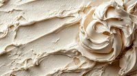 Creamy vanilla buttercream frosting swirled in decorative rose pattern with smooth textured background, macro food photography for bakery and dessert marketing.