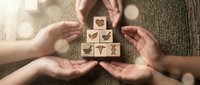 Hands protecting wooden blocks with healthcare and medical icons symbolizing health insurance coverage and wellness protection services.