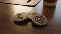 Wooden contact symbols with phone and email icons on desk surface next to laptop and coffee cup for business communication.