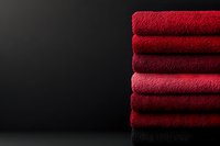 Stack of folded red and black terry towels on dark background with copy space for spa, hotel, or bathroom decor concepts.